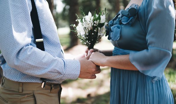 Intimate moment of a newlywed couple holding hands with a bouquet, symbolizing love and togetherness.