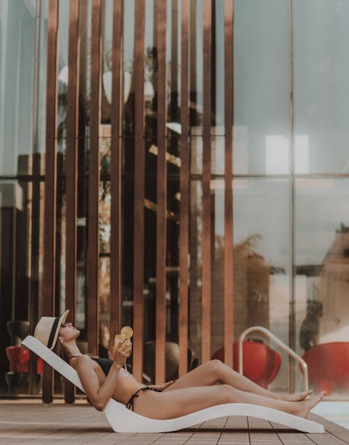 Woman in Black Bikini Relaxing on the Sun Lounger while Holding a Glass of Juice