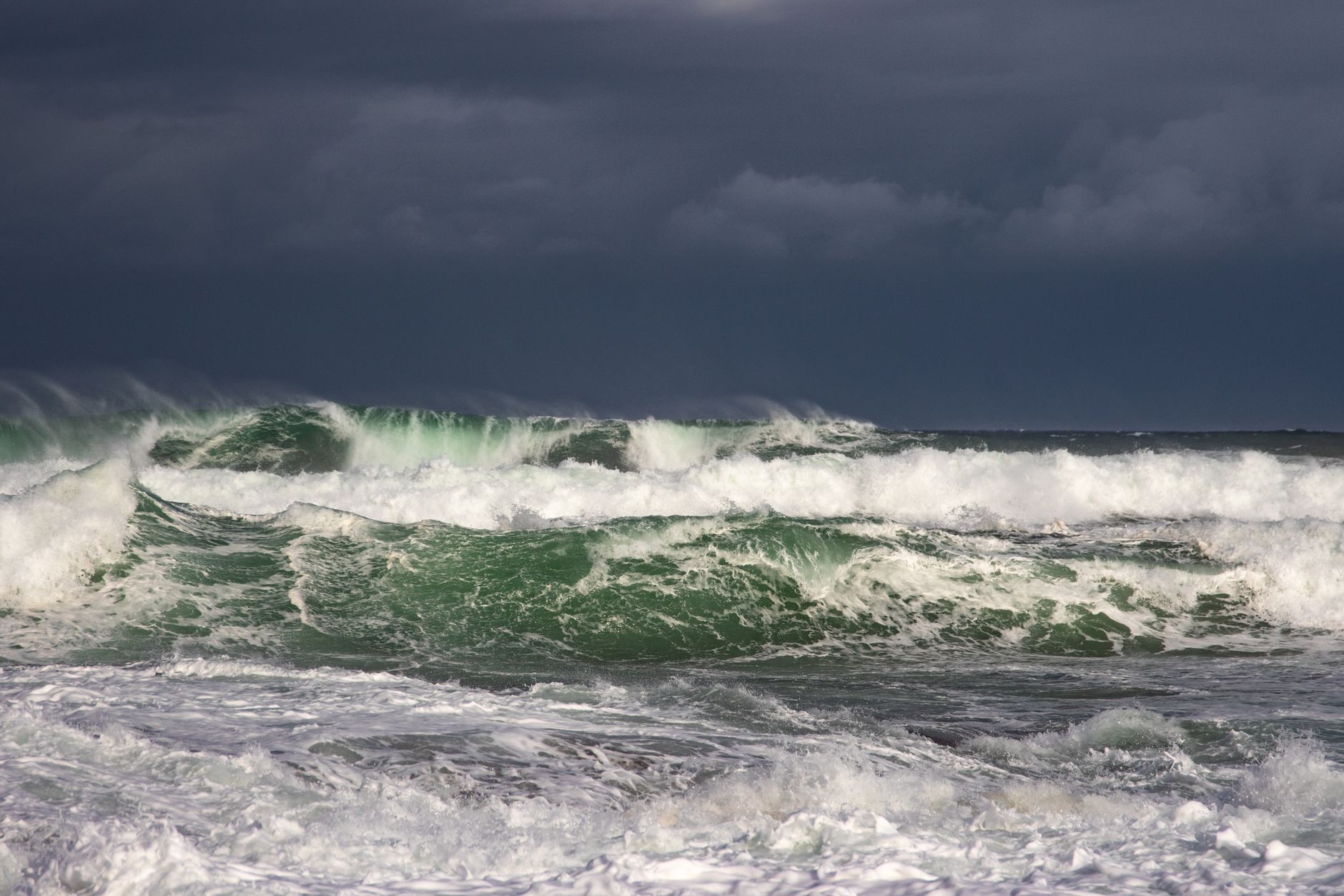 Powerful ocean waves crash under dark stormy clouds, capturing nature's raw force. — free online jigsaw puzzle on JigsawPuzzlesFreeOnline.org