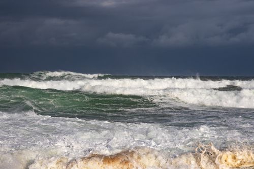 Free Powerful ocean waves crash beneath a moody, cloudy sky, showcasing nature's raw energy. Stock Photo
