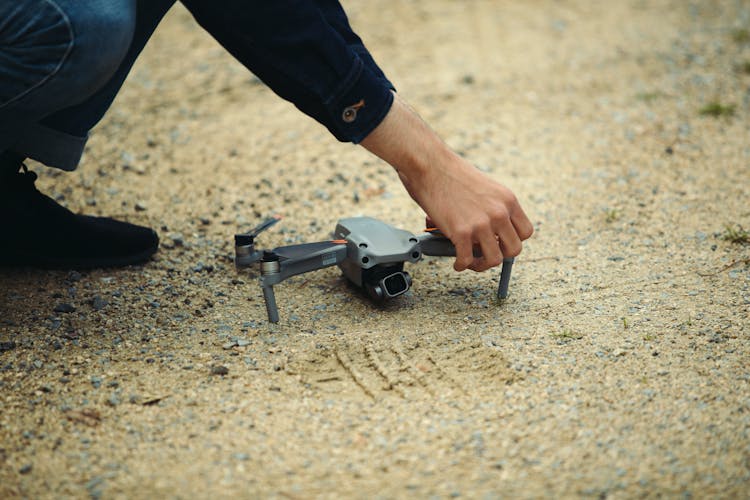 A Person Picking The Drone On The Sandy Shore