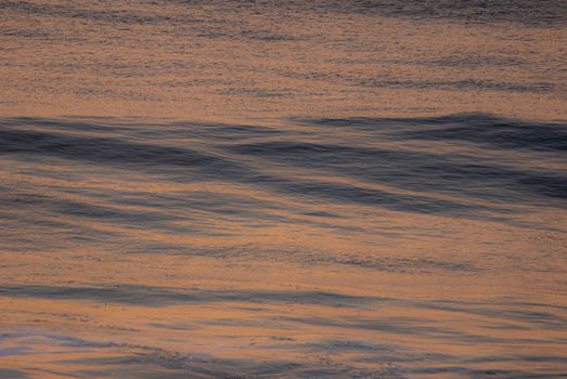 A tranquil scene of ocean waves with a warm glow at twilight, creating a peaceful atmosphere.