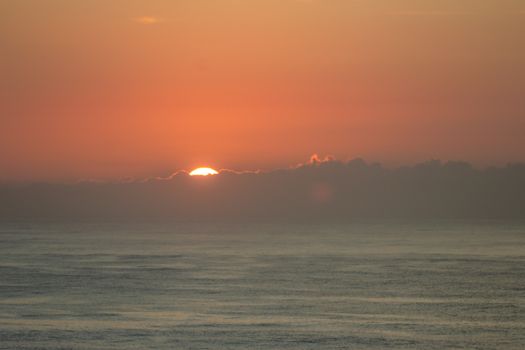 A beautiful sunset over the ocean with dramatic clouds and a serene ambiance.