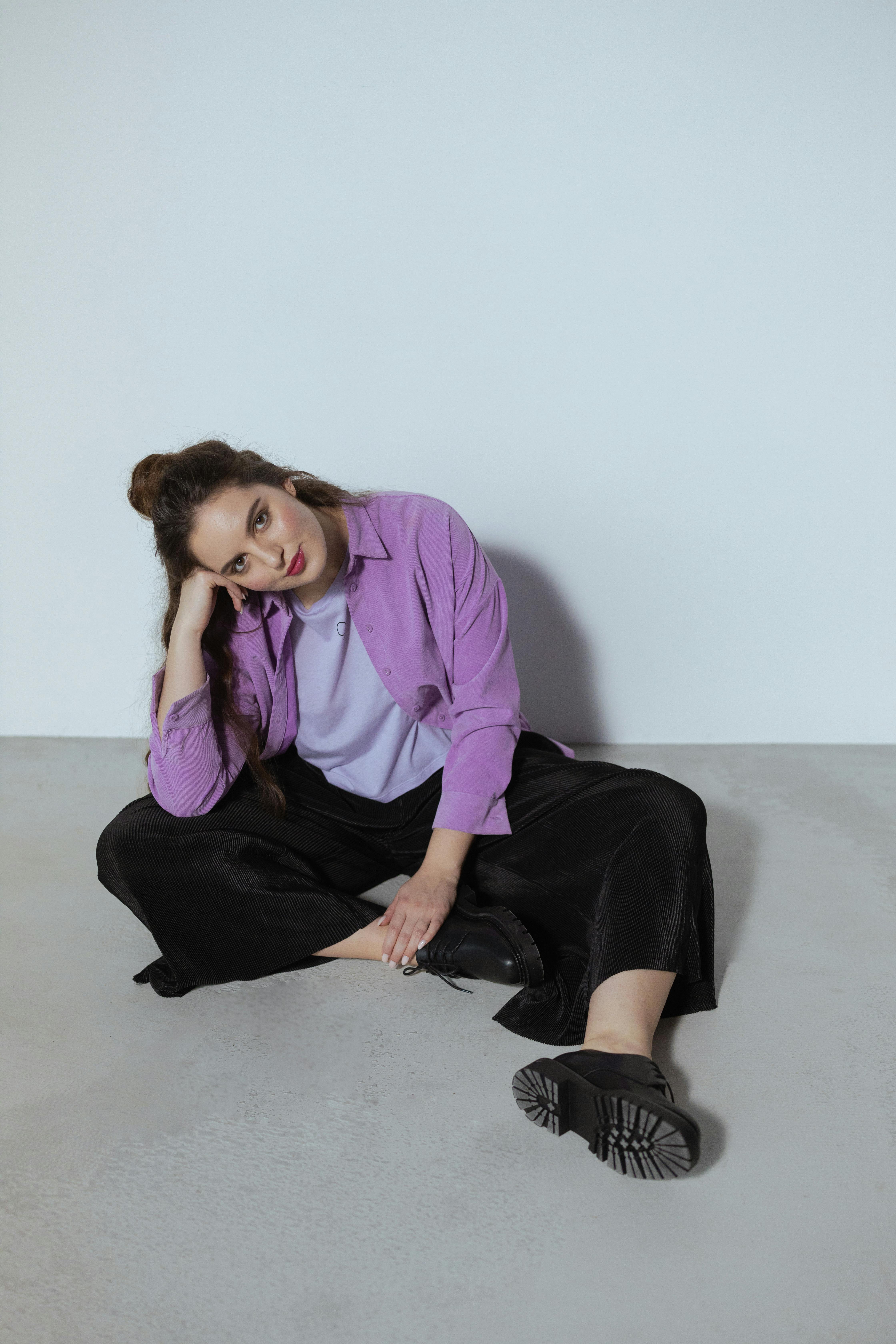 时尚的女人在紫色的顶部坐在室内与一个轻松的姿势和现代风格