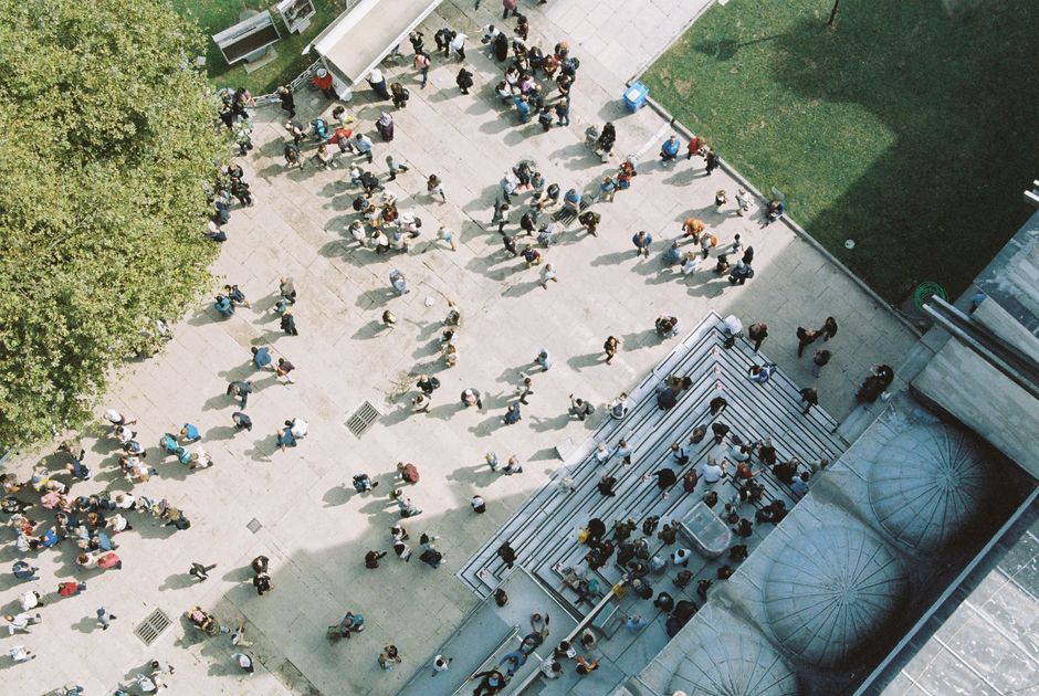 An aerial shot capturing a bustling city plaza filled with diverse crowds on a sunny day.