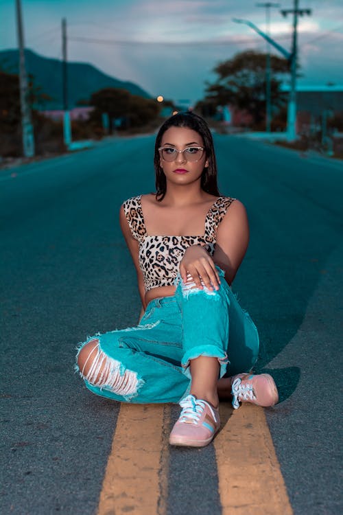 Woman in Tank Top Sitting in the middle of the Road