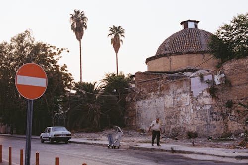 Photo of a Man Walking Near a Road Signage