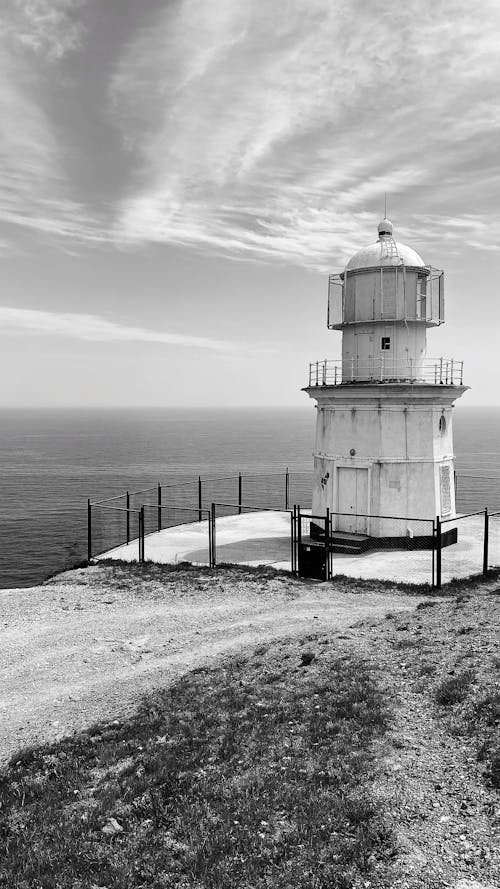 Free Black and white of old Meganom Lighthouse located on rocky cape above wavy sea against cloudy sky Stock Photo
