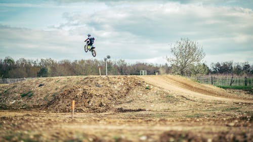 A Person Riding a Motor and Jumped Under White Sky during Daytime