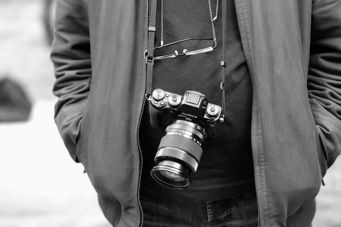 Grayscale Photo of a Person Carrying a Camera · Free Stock Photo