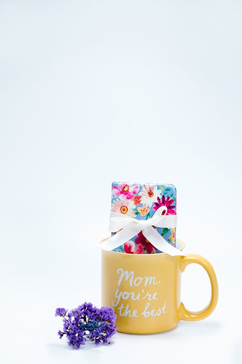 A Present in a Mug Beside Purple Flowers