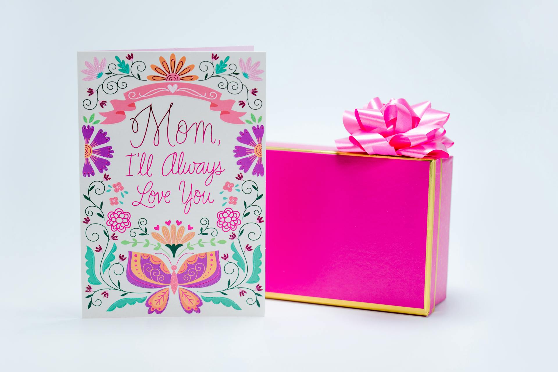 A beautiful Mother's Day card with floral design next to a pink gift box, perfect for gifting.