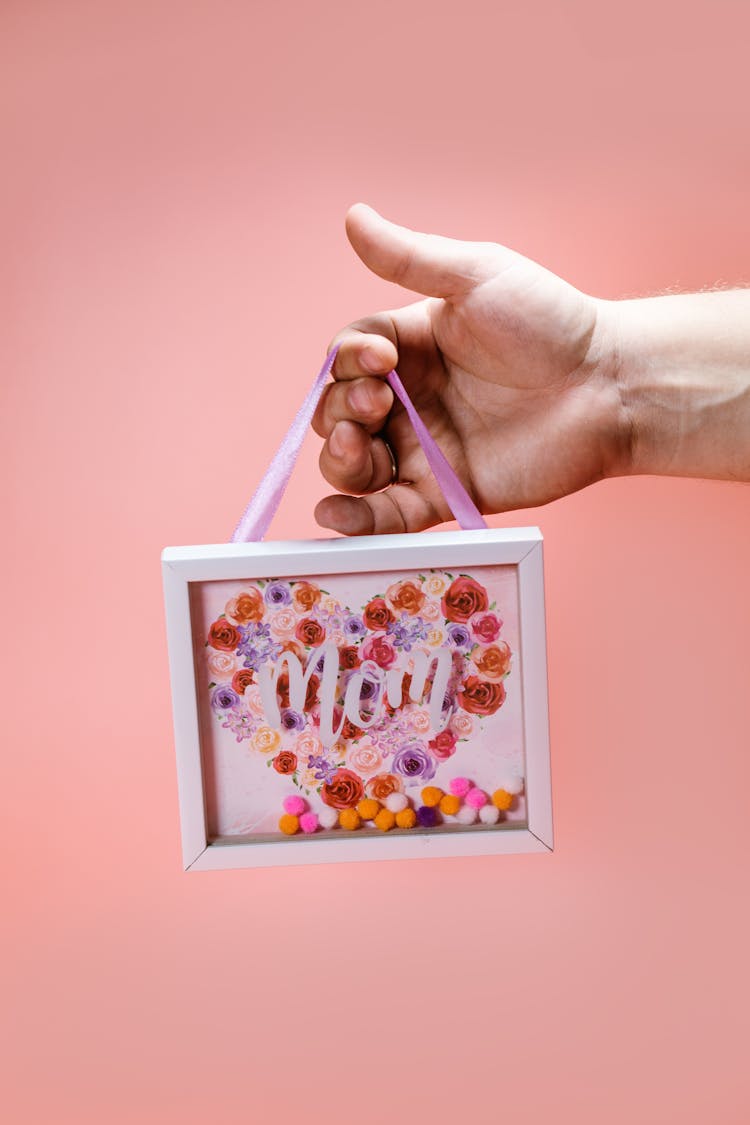 A Person Holding A Shadow Box With Flowers And Printed Mom On Glass