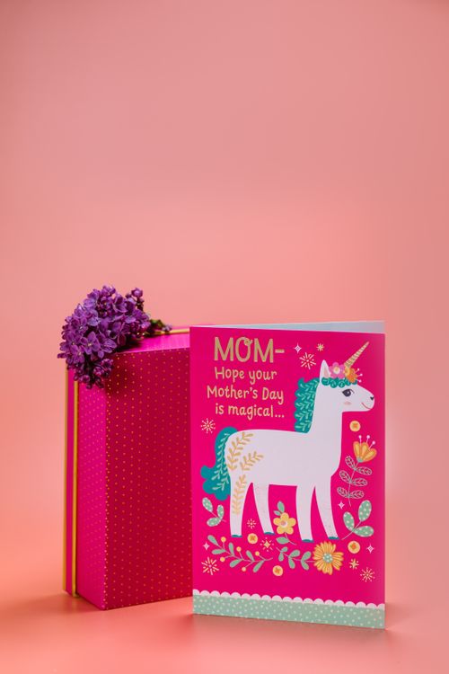 Free Bright Mother's Day card featuring a unicorn and flowers on a peach background. Stock Photo