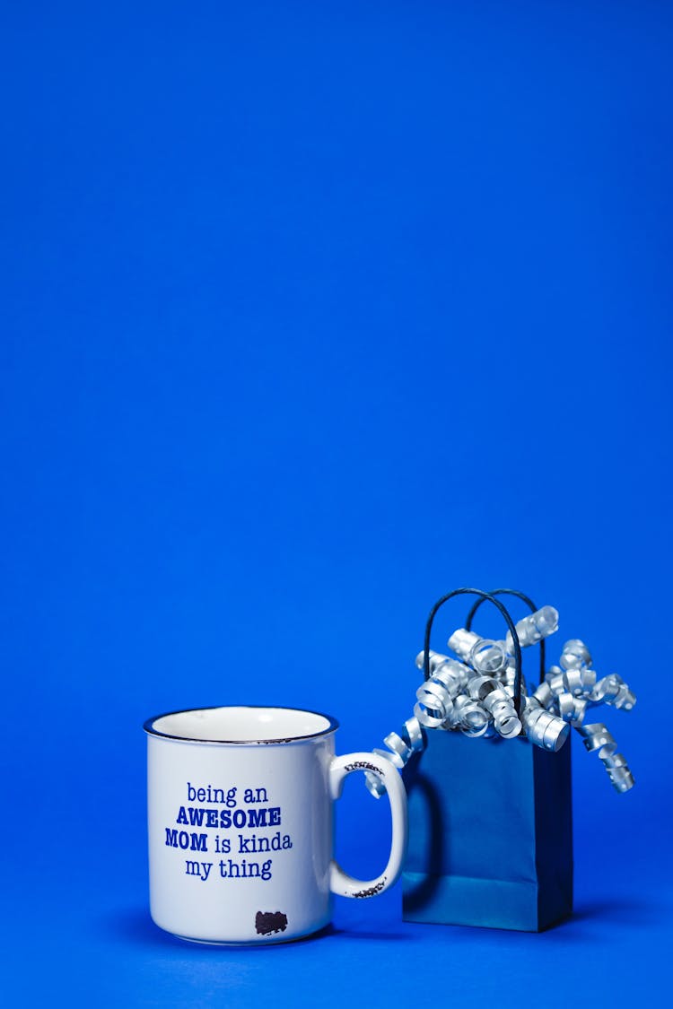 Ceramic Mug With Printed Text And A Paper Bag With Ribbons