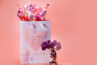 A charming Mother's Day gift bag with decorative flowers against a soft pink background.