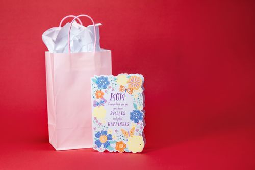 Free A colorful Mother's Day card with a gift bag against a red backdrop. Perfect for celebrations. Stock Photo