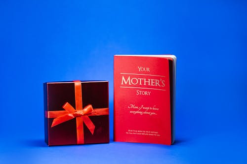 Free Close-Up Shot of a Book and a Red Gift Box on a Blue Surface Stock Photo