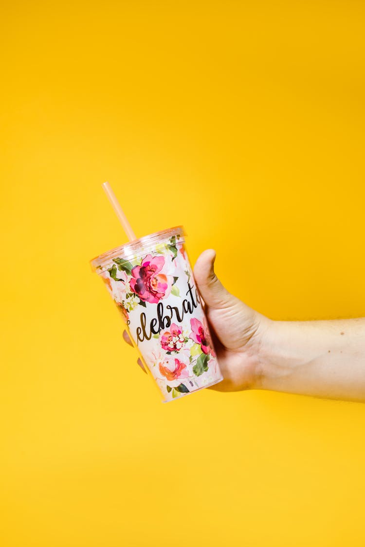 A Person Holding A Tumbler With A Floral Design