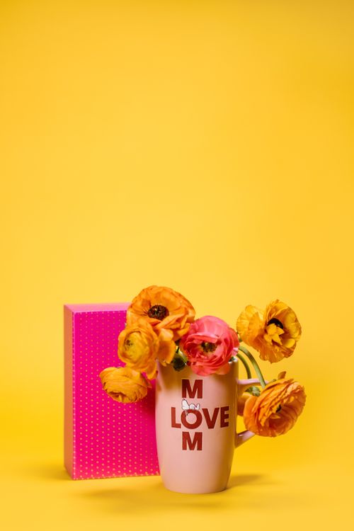 Free Bright floral arrangement in love-themed mug on yellow background. Stock Photo