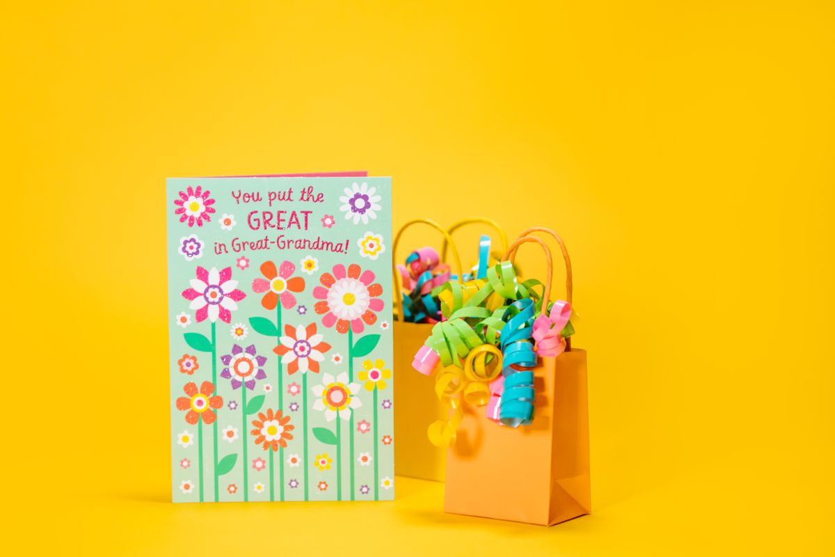 A floral greeting card next to a gift bag