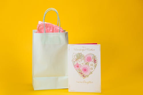 Free Close-Up Shot of a Gift and a Card on a Yellow Surface Stock Photo
