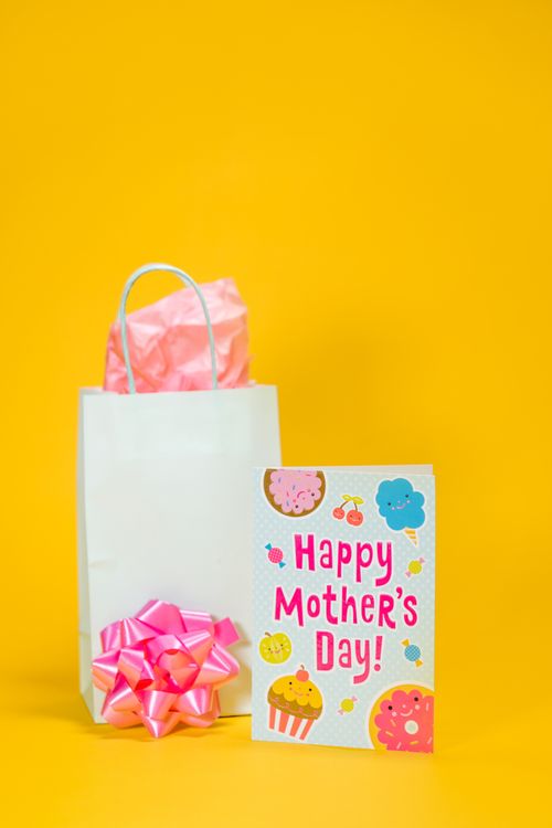 Free Vibrant Mother's Day gift display with greeting card and gift bag, perfect for celebration imagery. Stock Photo
