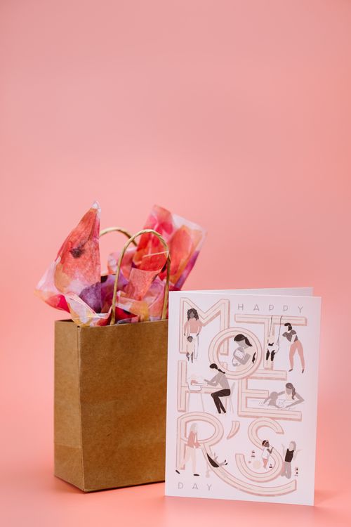 Free Elegant Mother's Day gift bag with a floral-themed card on a pink background. Stock Photo