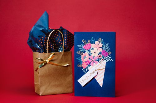 Free A Mother's Day card with a gift bag against a vibrant red background. Stock Photo