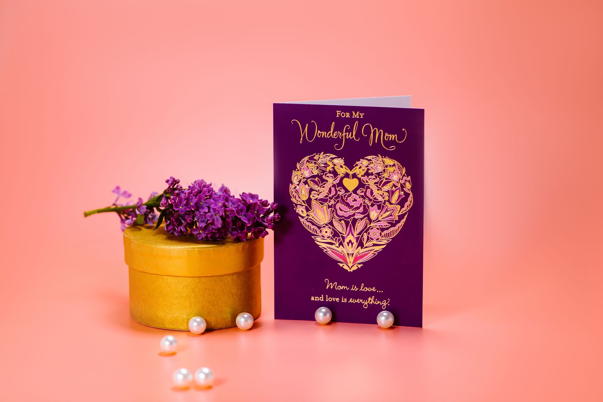 Charming Mother's Day card with purple design, lilac flowers and pearls on peach background, ready for gifting.