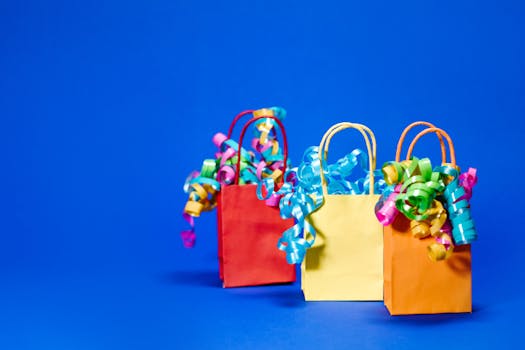 Vibrant paper gift bags with curly ribbons against a solid blue background.