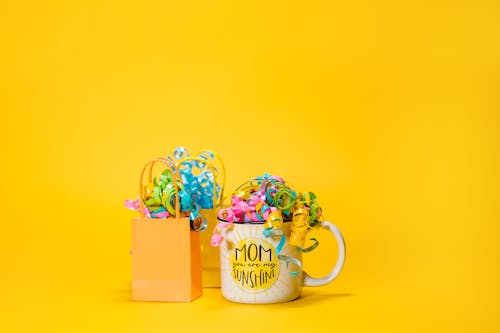 A Mug beside Paper Bags with Decorative Ribbons