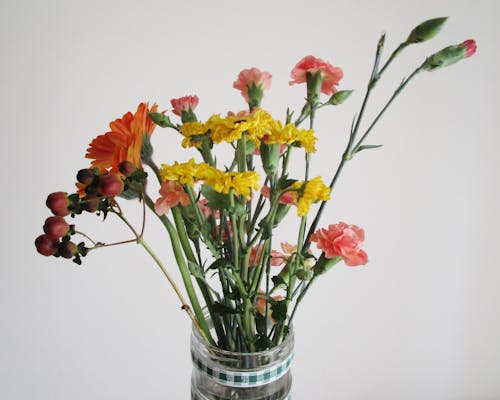 빨간색과 노란색 꽃과 투명 유리 꽃병