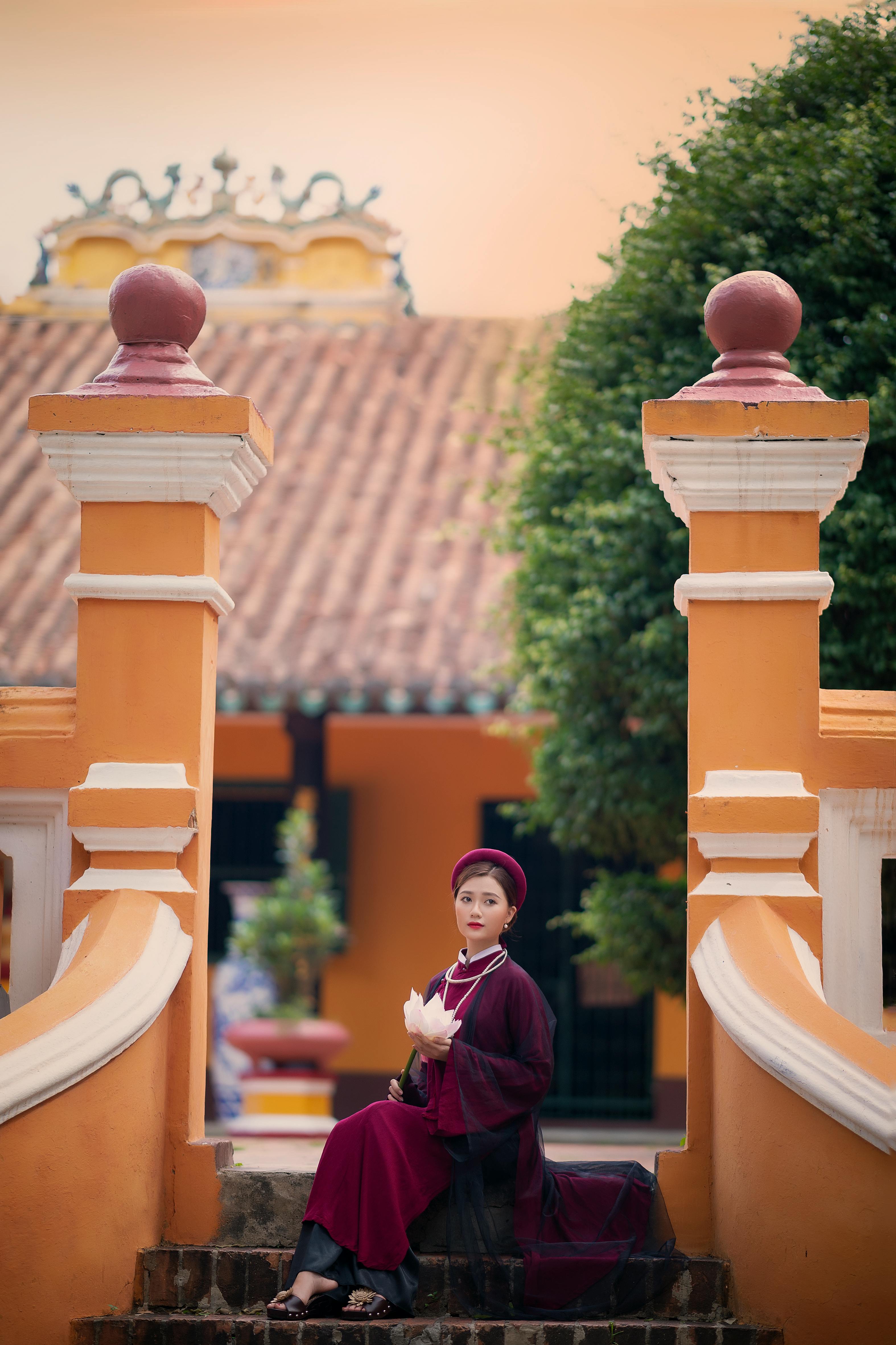 a woman wearing ao dai sitting by the stairs