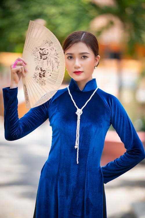 Kostnadsfri bild av asiatisk kvinna, blå klänning, håller