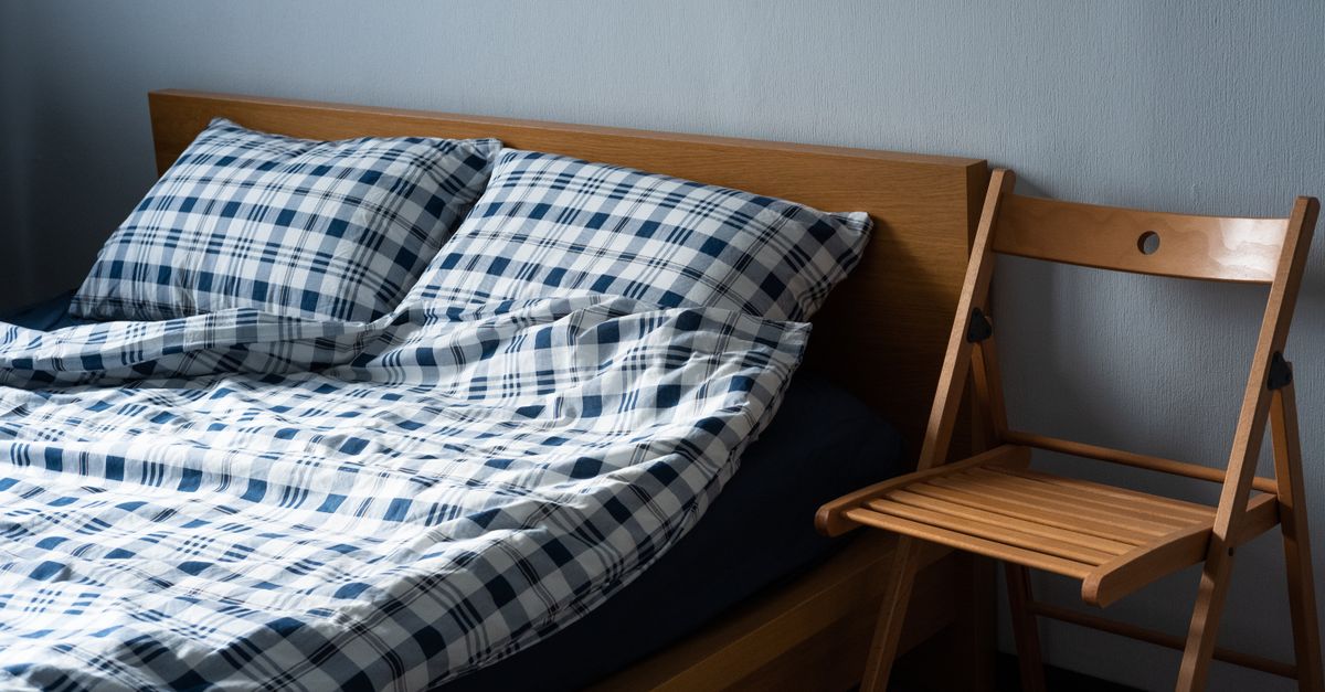 A styled bedroom with a layered bed, folded throw and clear surfaces