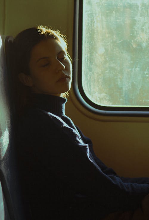 Free Side view of young female passenger with closed eyes sitting near window and having nap during ride in transport Stock Photo