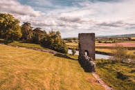 河边的历史遗址景观宁静，四周环绕着郁郁葱葱的绿色植物，非常适合自然爱好者