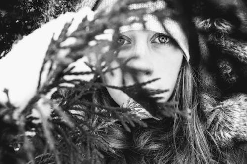 Grayscale Photo Of Woman Behind Leaves