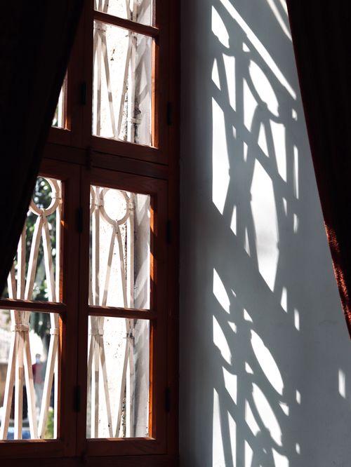Free Elegant shadows cast through a vintage wooden window with ornate grille design. Stock Photo