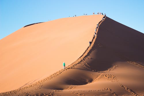 Free People Walking on a Sand Dune Stock Photo