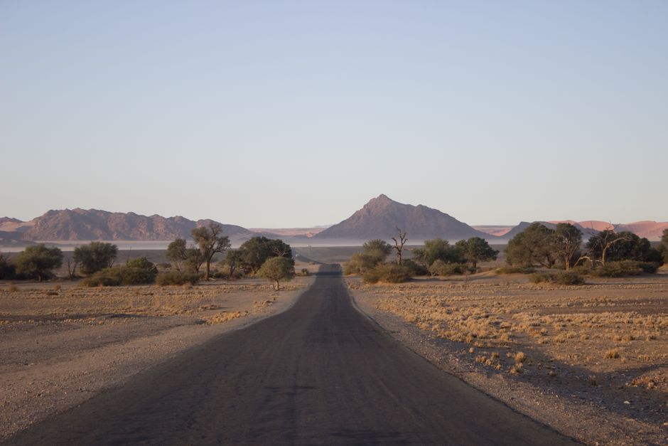 Scenic view of a lonely road through Namibia's desert landscape leading to distant mountains.
