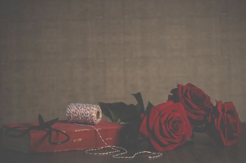 Free A classic still life with red roses, a vintage book, and crafting materials, ideal for romantic themes. Stock Photo