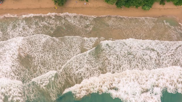 A breathtaking aerial view of the shoreline in Limón, Costa Rica, with waves crashing on the sandy beach.