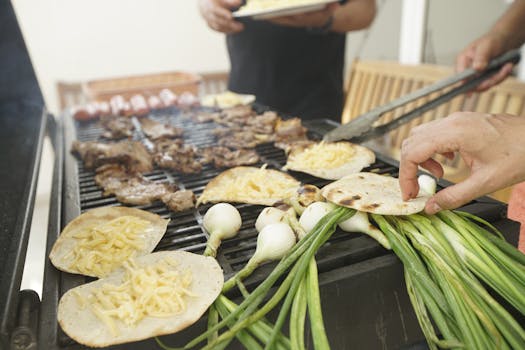 Delicious meat and cheese tortillas grilling alongside fresh scallions on a charcoal grill.