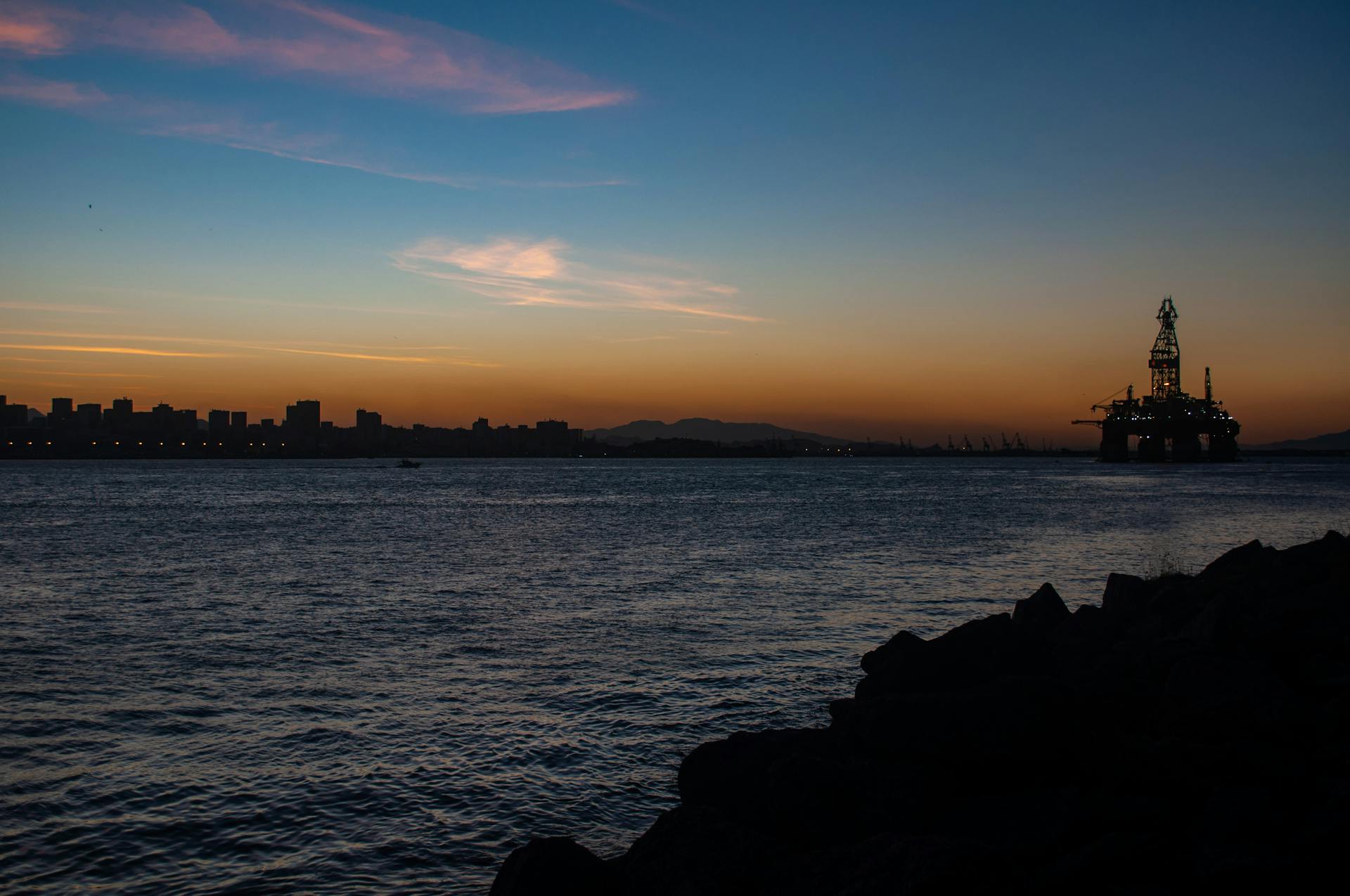 Silhouette of an oil rig against a vibrant sunset over the waters of Rio de Janeiro, Brazil.