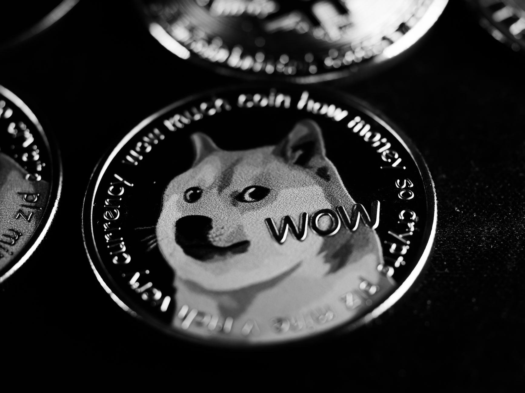 Close-up black and white image of a Dogecoin cryptocurrency coin with engraved text.