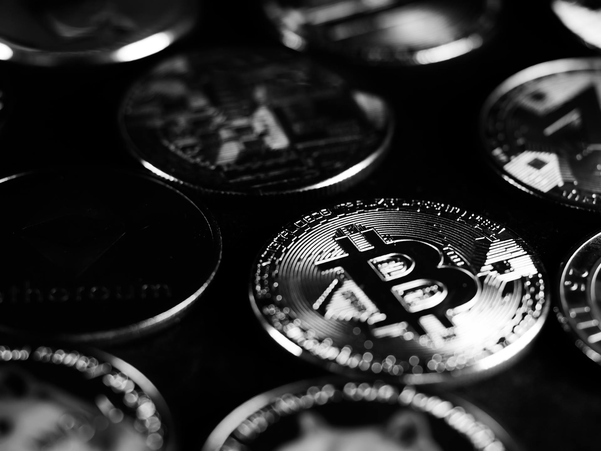 Monochrome close-up shot of Bitcoin and cryptocurrency coins, capturing digital currency essence.