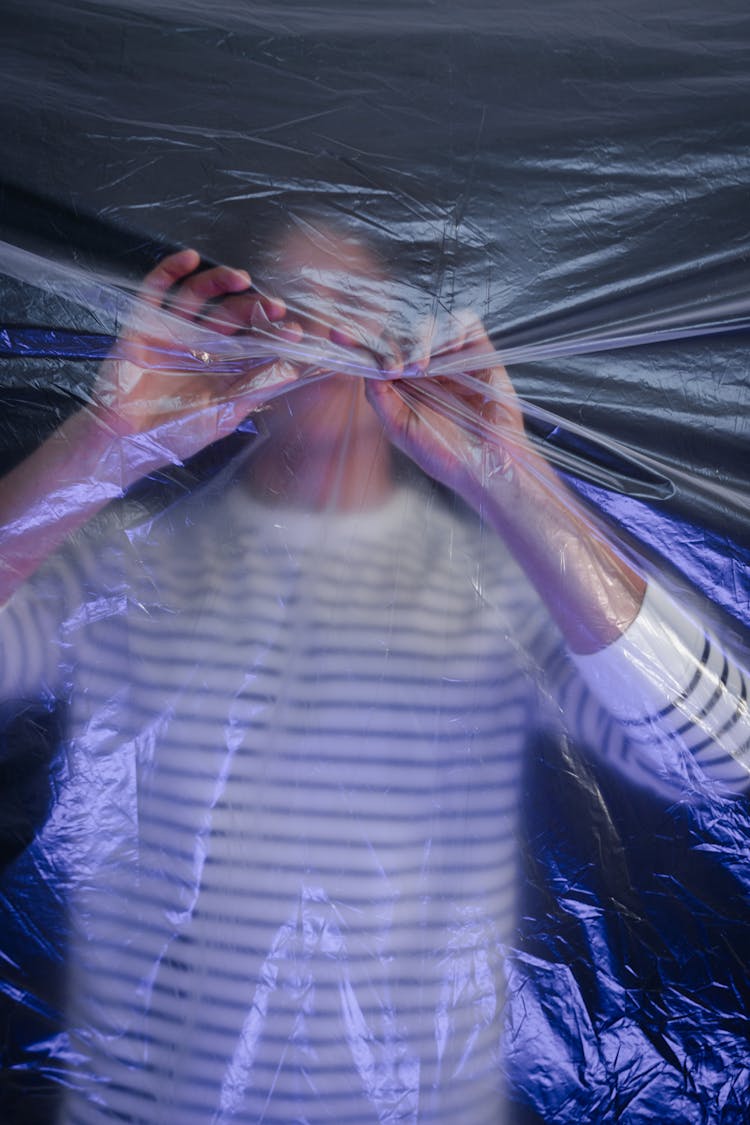 Person In Stripes Long Sleeve Shirt Ripping A Plastic In Front Of Him