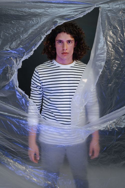 Free Artistic portrait of a young man in a striped shirt breaking through plastic. Stock Photo